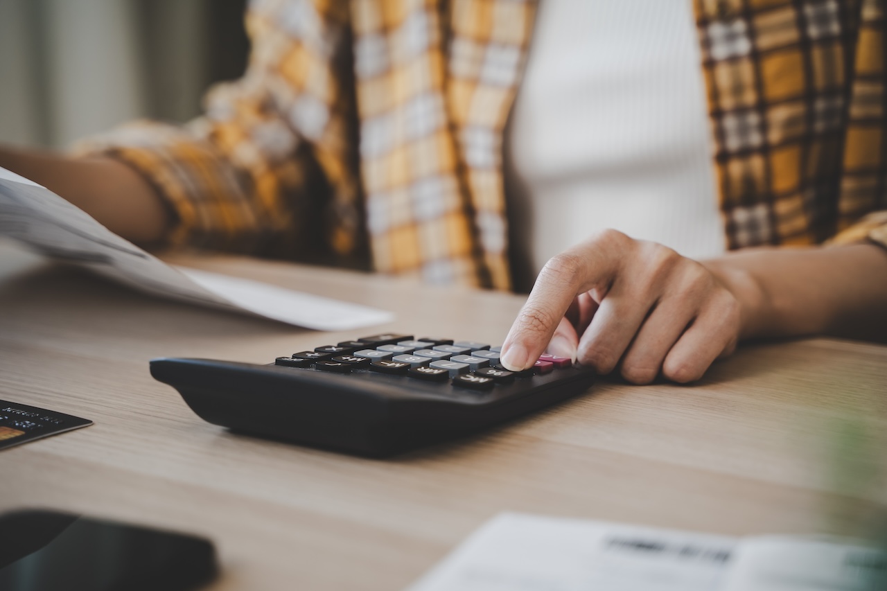 Closely Examining Financial Matters: Person's Hand Engaged In Precise Calculation Of Bills Using A Calculator