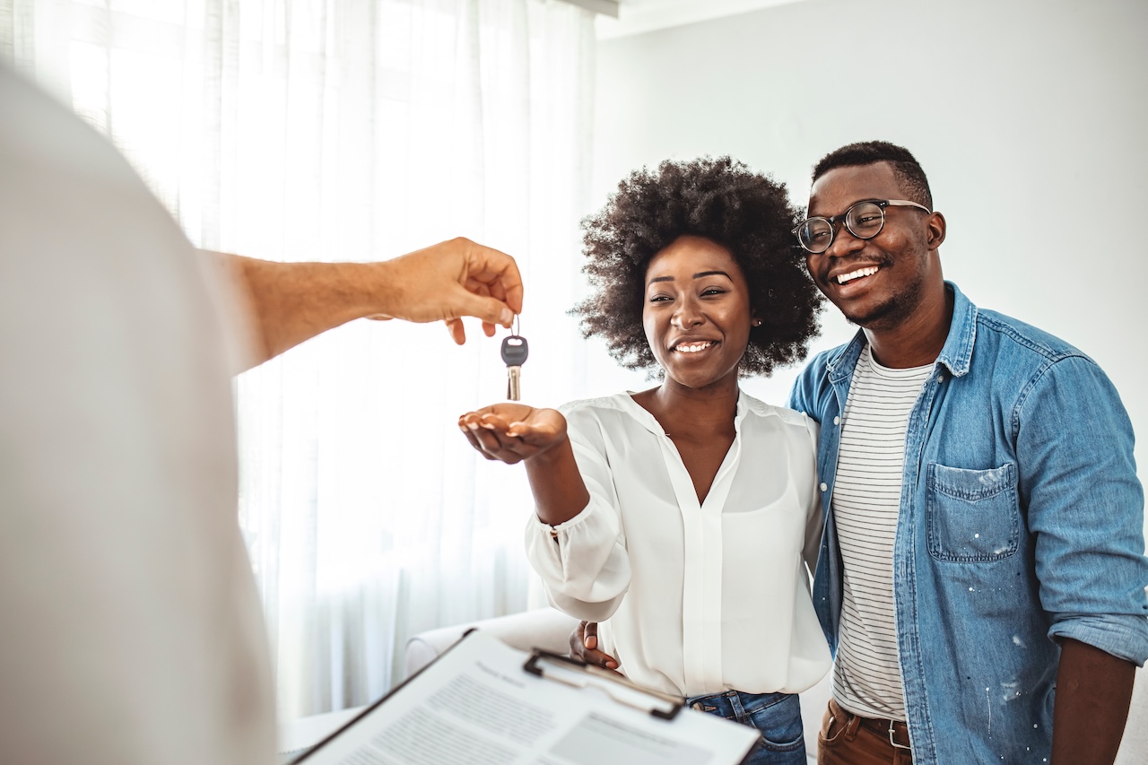 Pareja Recibiendo Las Llaves De Su Nueva Casa. Portrait Of Financial Adviser Congratulating To A Young Couple For Buying A New House. Familia afroamericana compra casa nueva