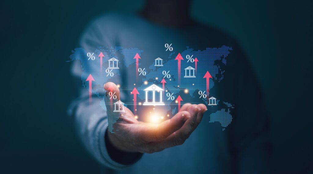 Bank Interest Rate Concept, Businessman Holding Global Bank Icon With Arrow Up And Increase Percentage Interest Rate Of Loan. Federal Reserve Or Central Bank Raising Policy. Debt Rate. Investment.